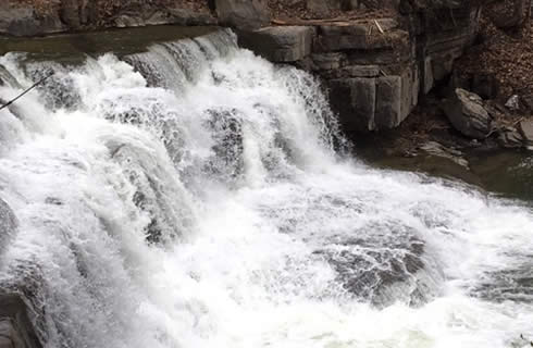 Frothing white water pours over a waterfall.