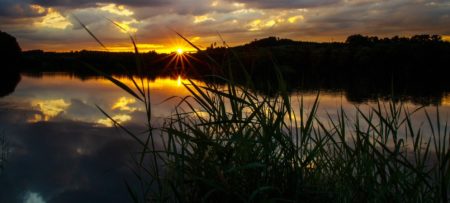 Beautiful yellow and orange sunset with speckled clouds over a smooth lake