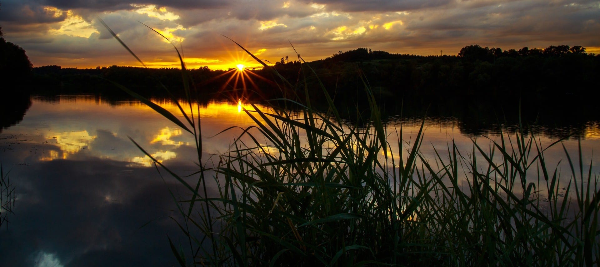 Beautiful yellow and orange sunset with speckled clouds over a smooth lake