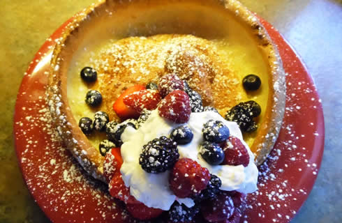 A dutch baby pancake topped with fresh berries and whipped cream.