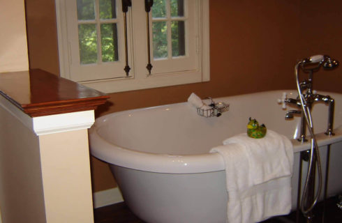 Freestanding white bathtub in an elegant bathroom with a white window.