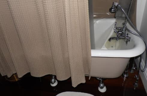 A free-standing bathtub with a beige shower curtain.