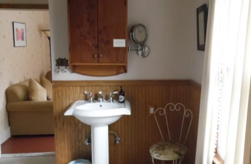 Bathroom with large window, wooden chair rail, a white sink and vanity cabinet.