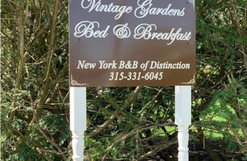 Brown metal sign on white and gold legs with text: Vintage Gardens Bed & Breakfast