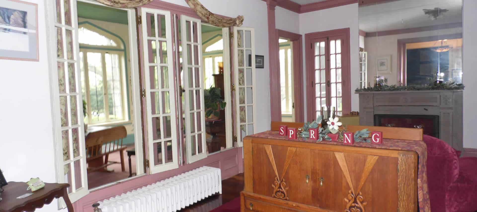 Parlor area with a grey fireplace, sofa and large wooden cabinet.